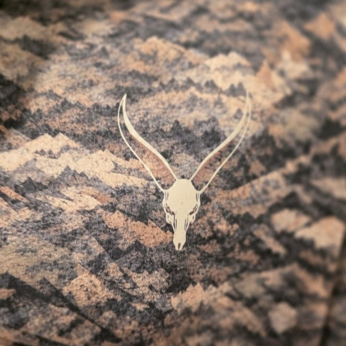 Close-up of the Seven Devils skull logo on the chest of the Grave Point Hoody in Canyon Ghost camo